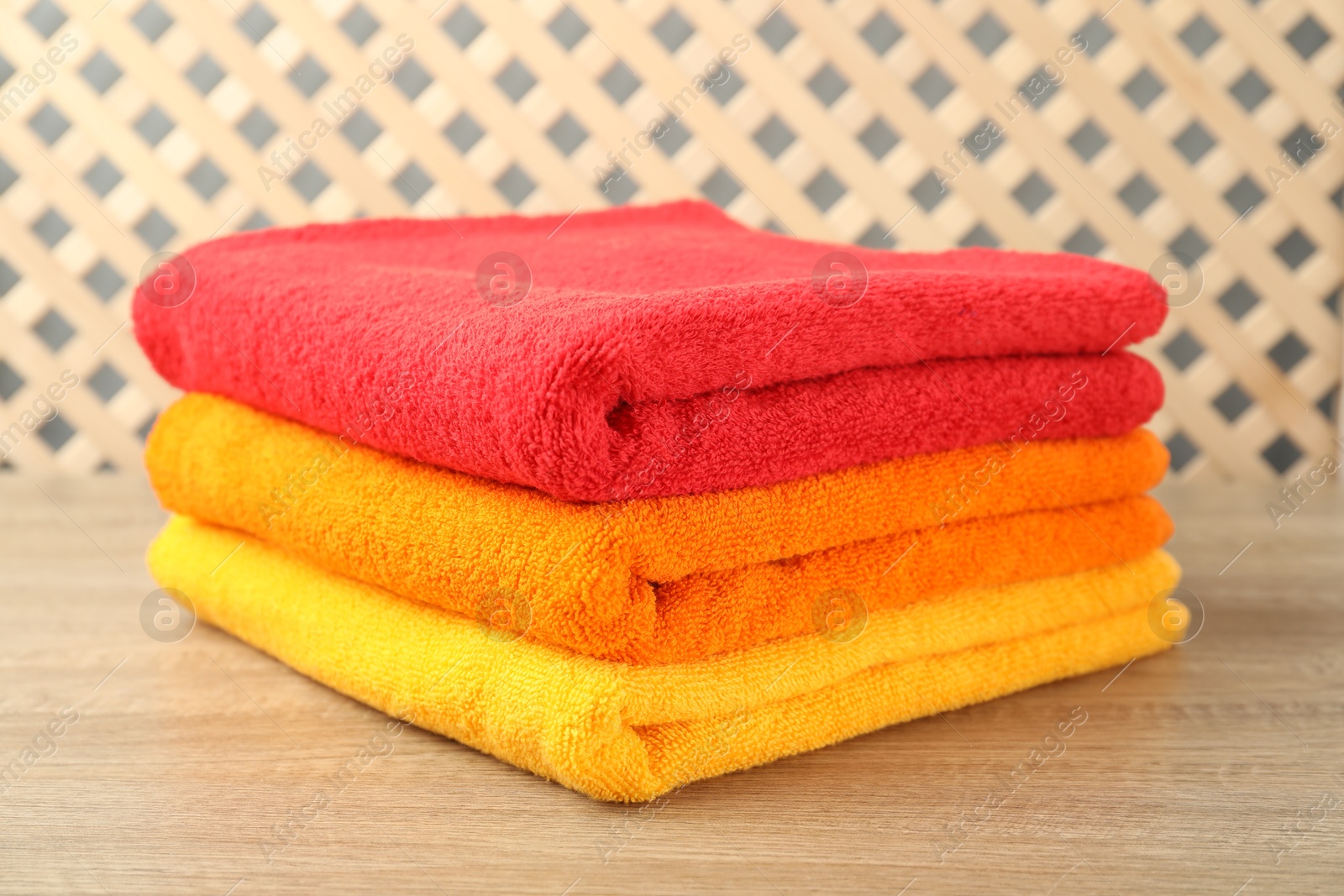 Colorful fresh terry towels on wooden table, closeup Photo of Colorful fresh terry towels on wooden table, closeup