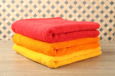 Photo of Colorful fresh terry towels on wooden table, closeup