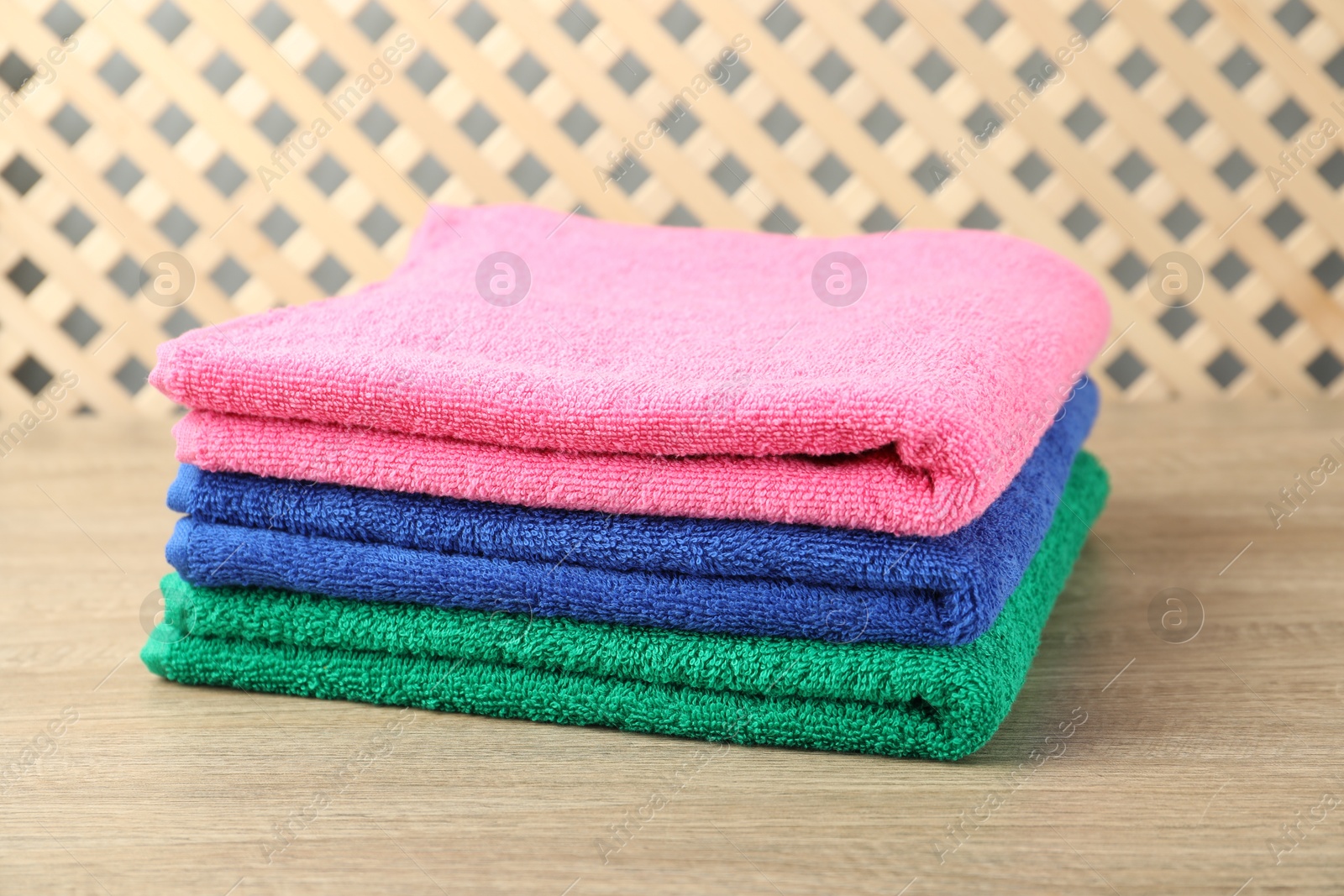 Photo of Colorful fresh terry towels on wooden table, closeup
