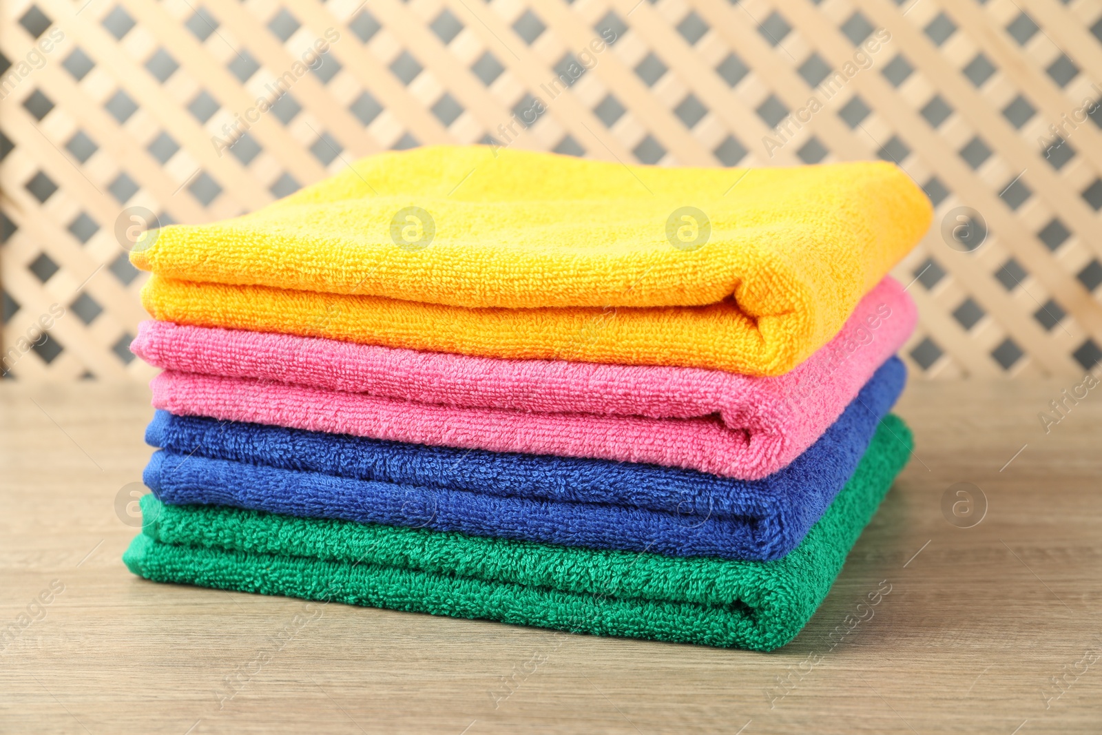 Photo of Colorful fresh terry towels on wooden table, closeup