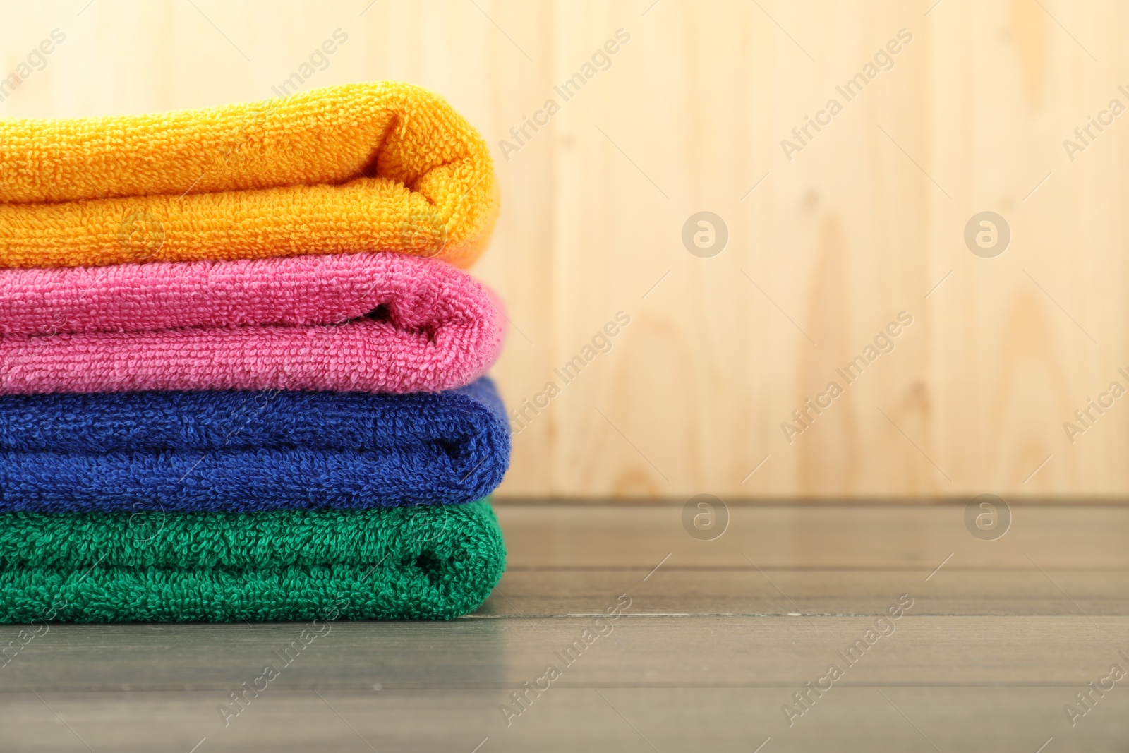 Photo of Colorful fresh terry towels on wooden table, closeup. Space for text