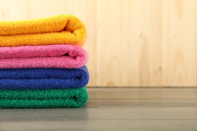 Photo of Colorful fresh terry towels on wooden table, closeup. Space for text