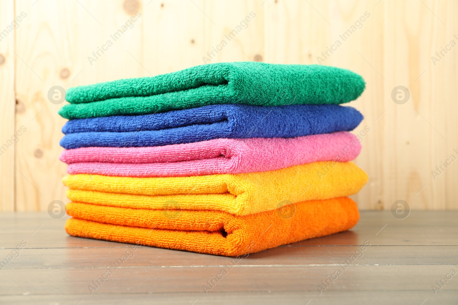 Photo of Colorful fresh terry towels on wooden table, closeup