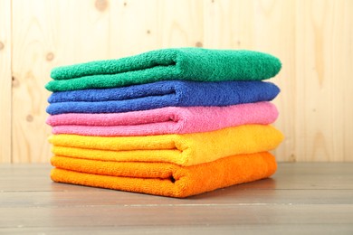 Photo of Colorful fresh terry towels on wooden table, closeup