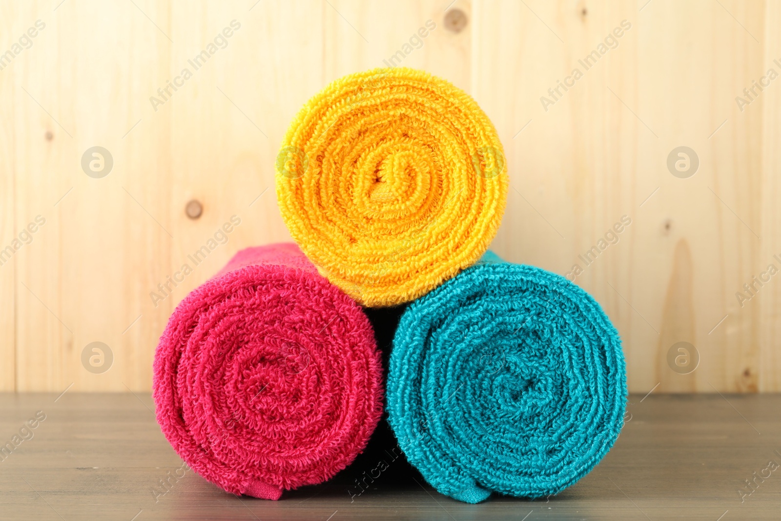 Photo of Colorful fresh terry towels on wooden table, closeup