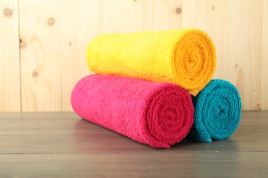 Photo of Colorful fresh terry towels on wooden table, closeup