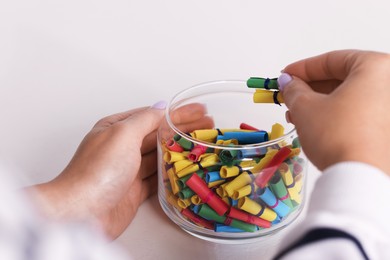 Photo of Woman with glass jar of colorful paper pieces at white table, closeup