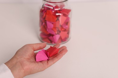 Photo of Woman with colorful paper pieces at white table, closeup