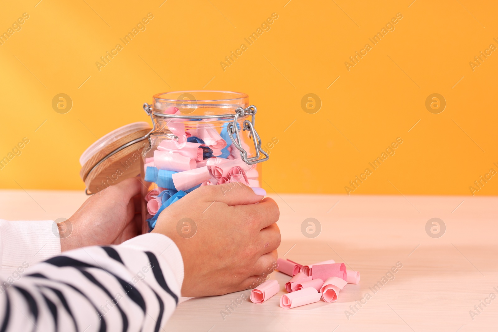 Woman with glass jar of color paper pieces at white wooden table, closeup. Space for text Photo of Woman with glass jar of color paper pieces at white wooden table, closeup. Space for text