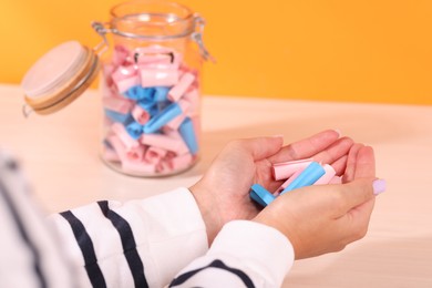 Photo of Woman with color paper pieces at white wooden table, closeup