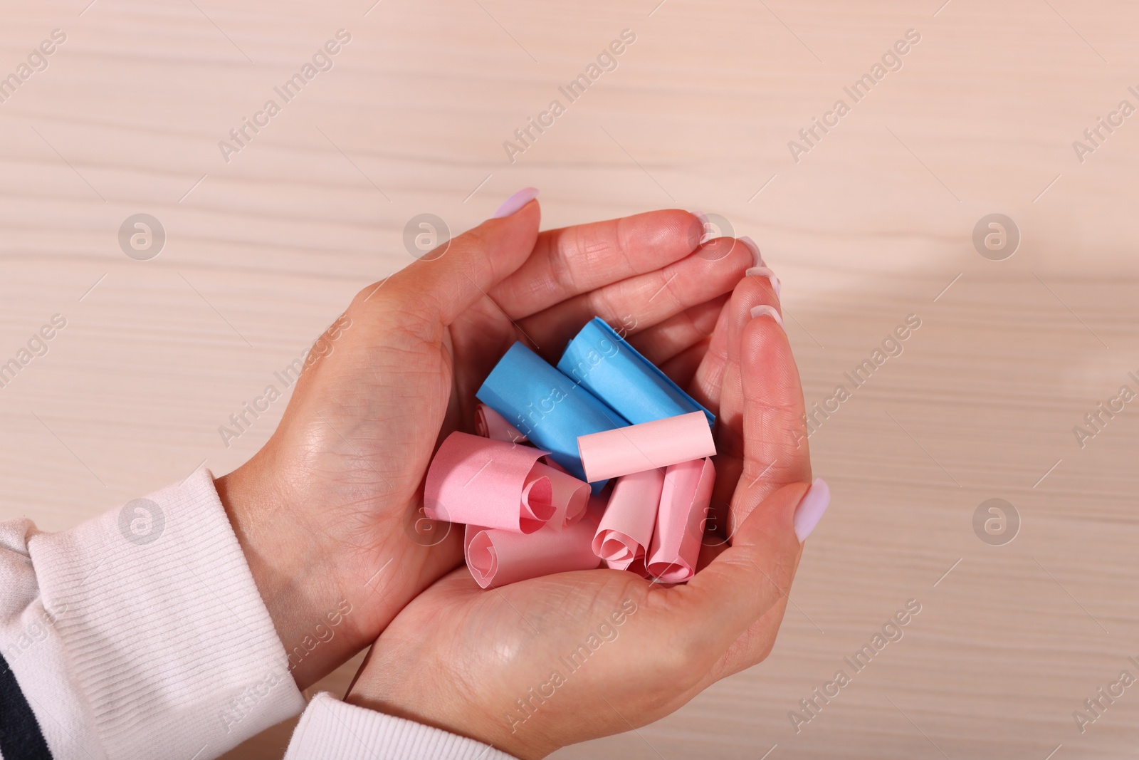 Woman holding color paper pieces at white wooden table, closeup Photo of Woman holding color paper pieces at white wooden table, closeup