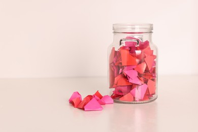 Photo of Color paper pieces in glass jar on light table, space for text