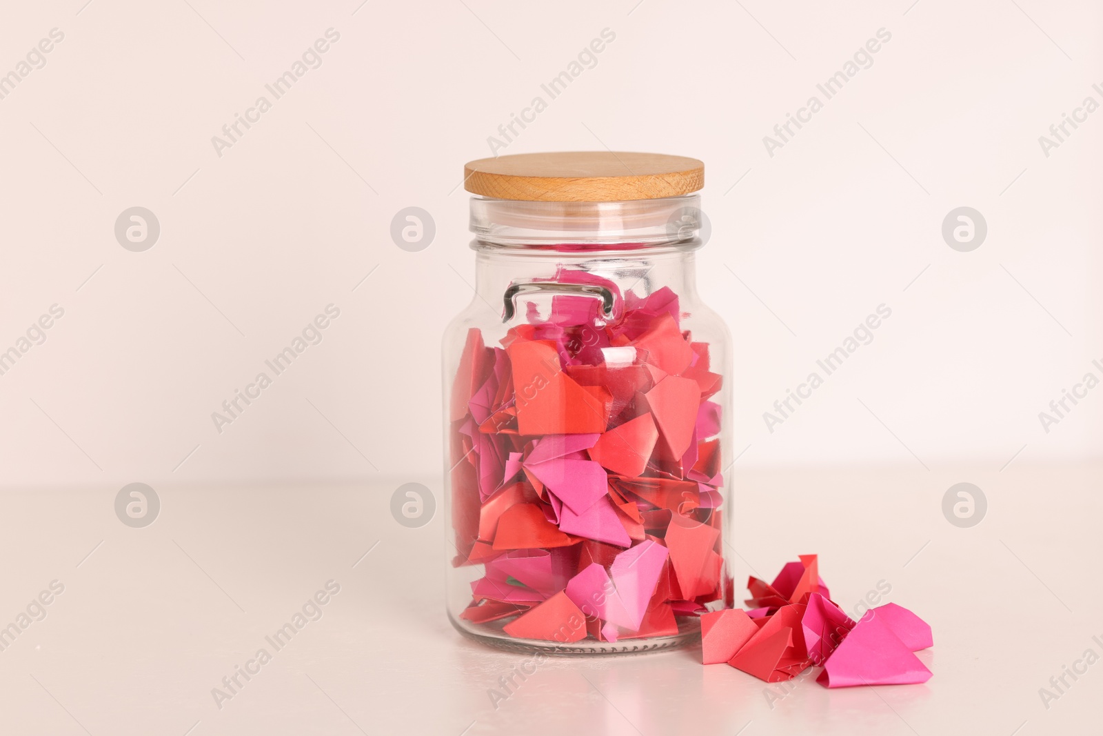 Color paper pieces in glass jar on light table Photo of Color paper pieces in glass jar on light table