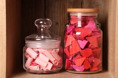 Photo of Color paper pieces in glass jars on wooden shelf
