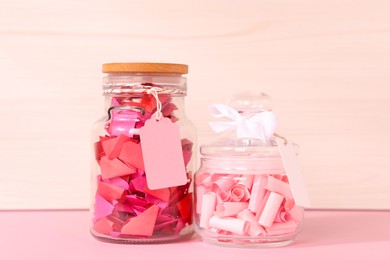 Photo of Color paper pieces in glass jars on pink table