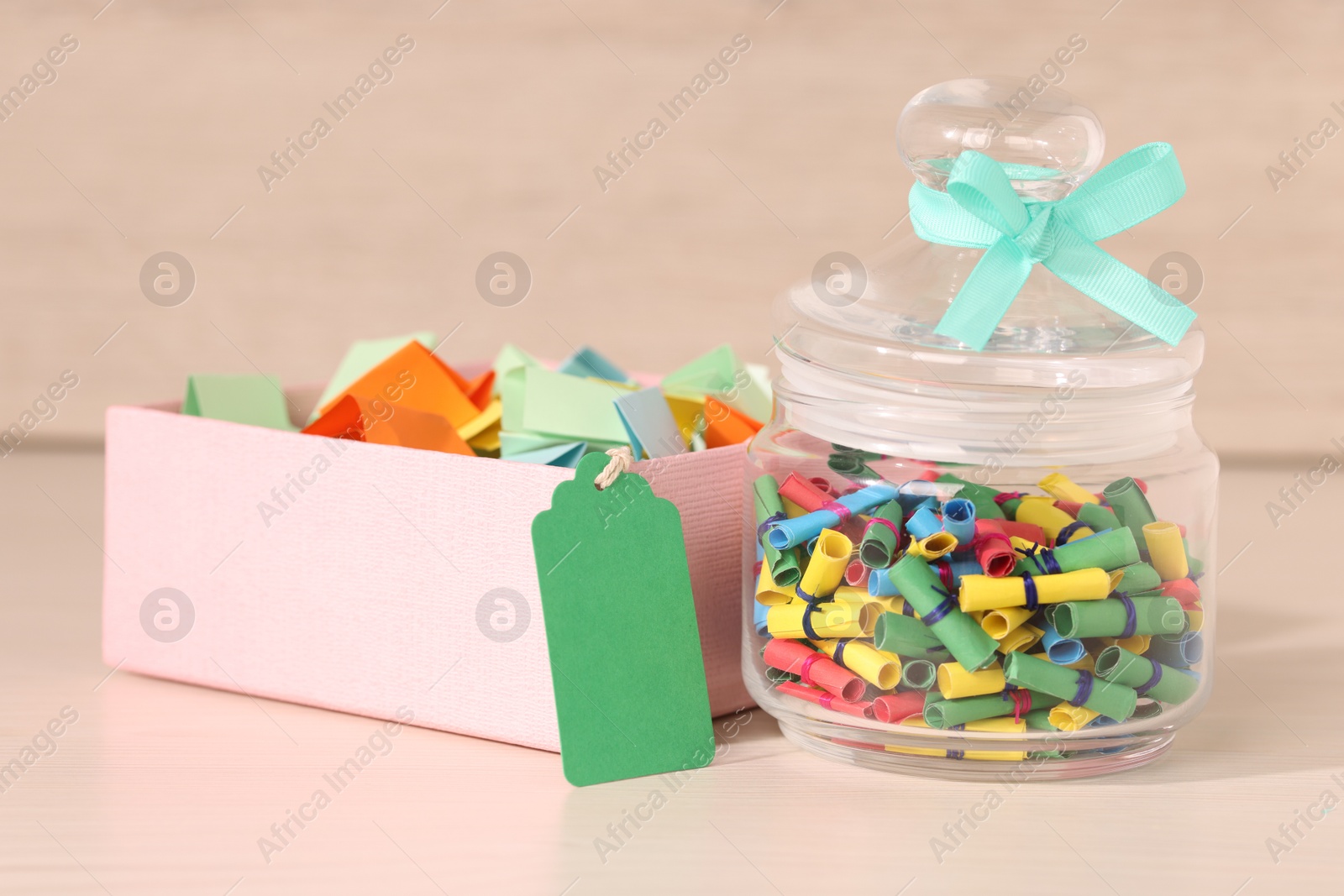 Color paper pieces in box and glass jar on light wooden table, closeup Photo of Color paper pieces in box and glass jar on light wooden table, closeup