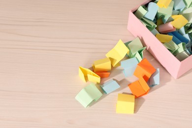 Photo of Color paper pieces on light wooden table, above view. Space for text