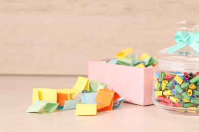 Photo of Color paper pieces on light wooden table, closeup. Space for text