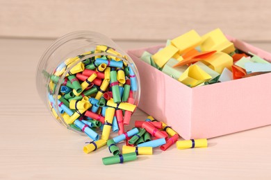 Photo of Color paper pieces on light wooden table, closeup