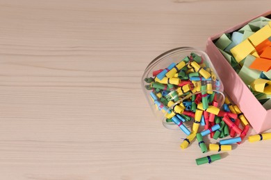 Photo of Color paper pieces on light wooden table, above view. Space for text