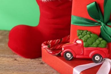Photo of Saint Nicholas day tradition. Red boot with sweets and gift boxes on wooden table, closeup