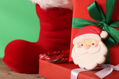 Photo of Saint Nicholas day tradition. Red boot, sweets and gift boxes on wooden table, closeup