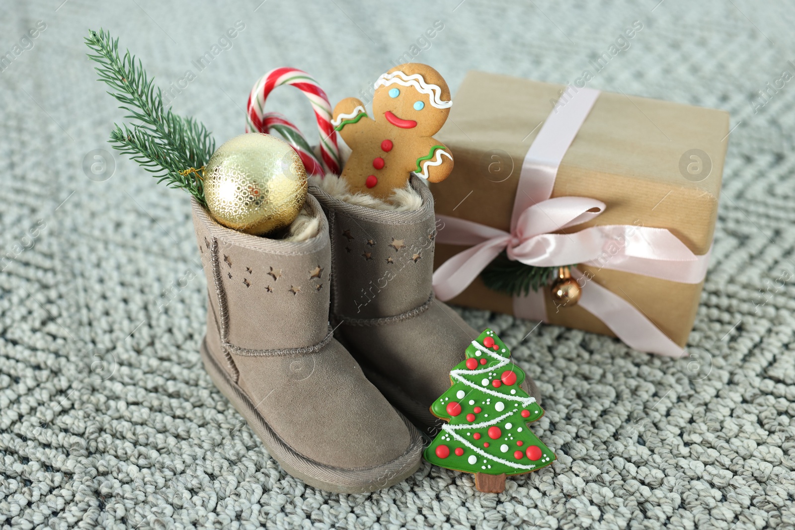 Photo of Saint Nicholas day tradition. Boots with sweets, gift box and festive decor on floor indoors