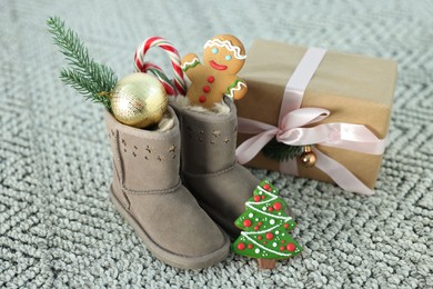 Photo of Saint Nicholas day tradition. Boots with sweets, gift box and festive decor on floor indoors