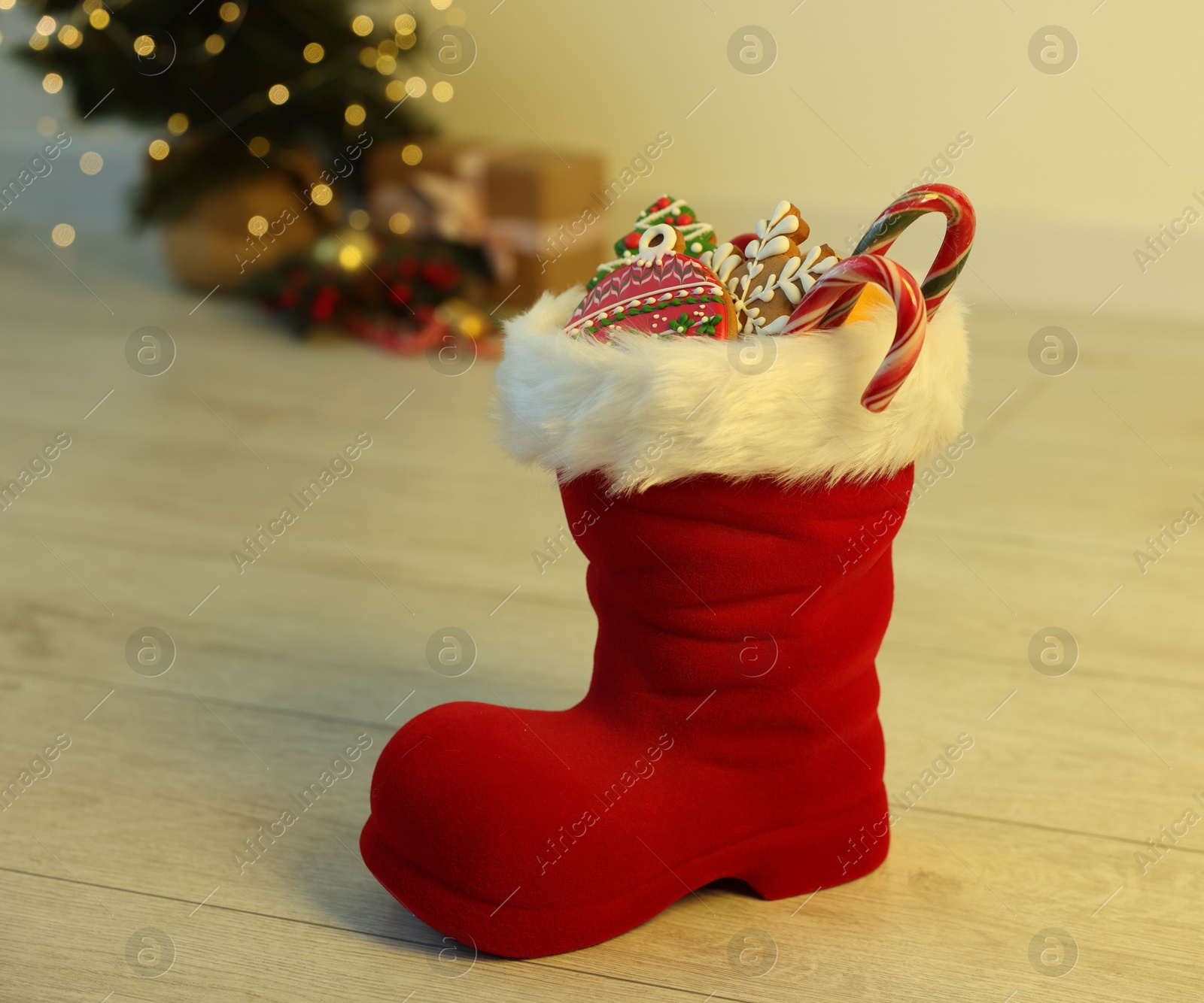 Photo of Saint Nicholas day tradition. Red boot with sweets on floor indoors