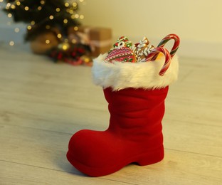 Photo of Saint Nicholas day tradition. Red boot with sweets on floor indoors