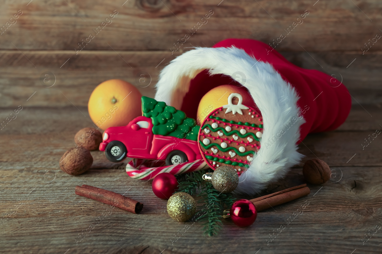 Photo of Saint Nicholas day tradition. Red boot with sweets, cinnamon sticks, walnuts and festive decor on wooden table