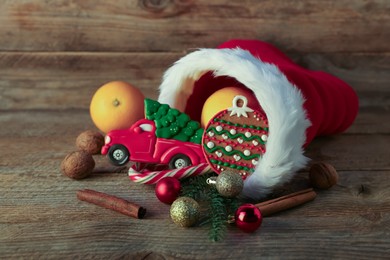 Photo of Saint Nicholas day tradition. Red boot with sweets, cinnamon sticks, walnuts and festive decor on wooden table