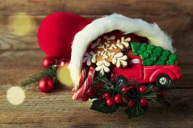 Photo of Saint Nicholas day tradition. Red boot with sweets and festive decor on wooden table, closeup