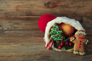 Photo of Saint Nicholas day tradition. Red boot with sweets and festive decor on wooden table, space for text