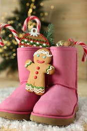 Photo of Saint Nicholas day tradition. Boots with sweets and artificial snow on floor indoors, closeup