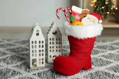 Photo of Saint Nicholas Day tradition. Red boot with treats and burning candles in room