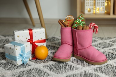 Photo of Saint Nicholas Day tradition. Child's boots with treats and gift boxes in room