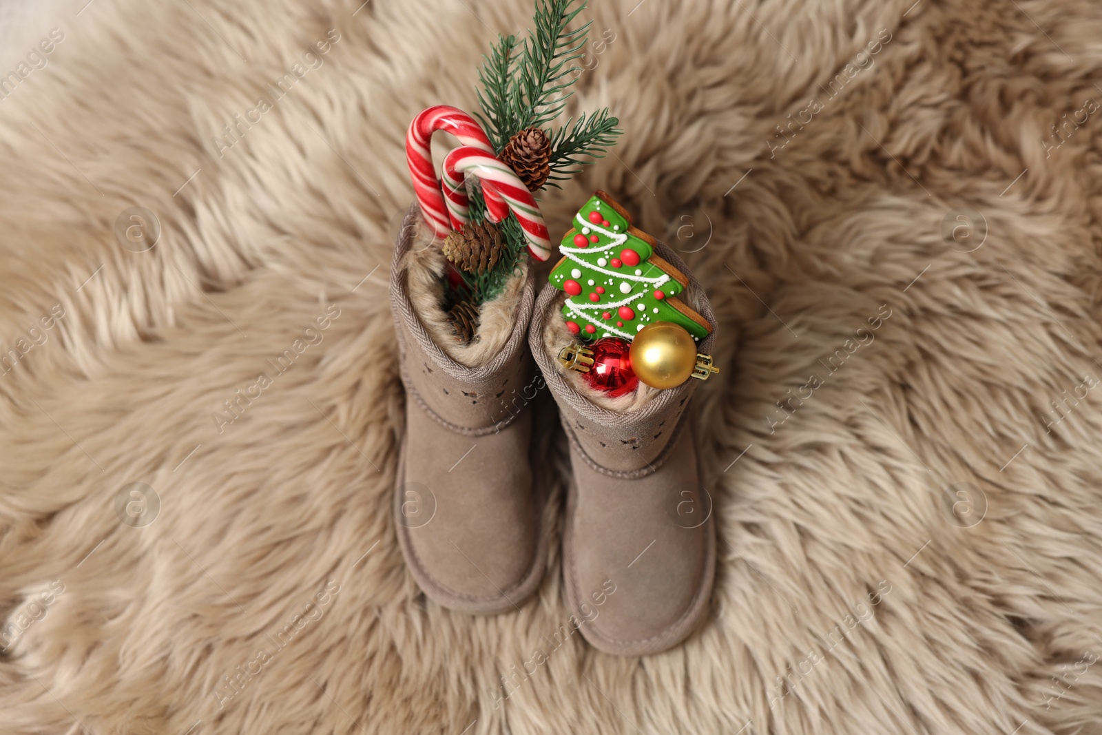 Photo of Saint Nicholas Day tradition. Child's boots with treats on fur rug, above view