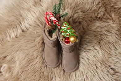 Photo of Saint Nicholas Day tradition. Child's boots with treats on fur rug, above view