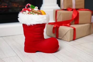 Photo of Saint Nicholas Day tradition. Boot with treats and gift boxes in room