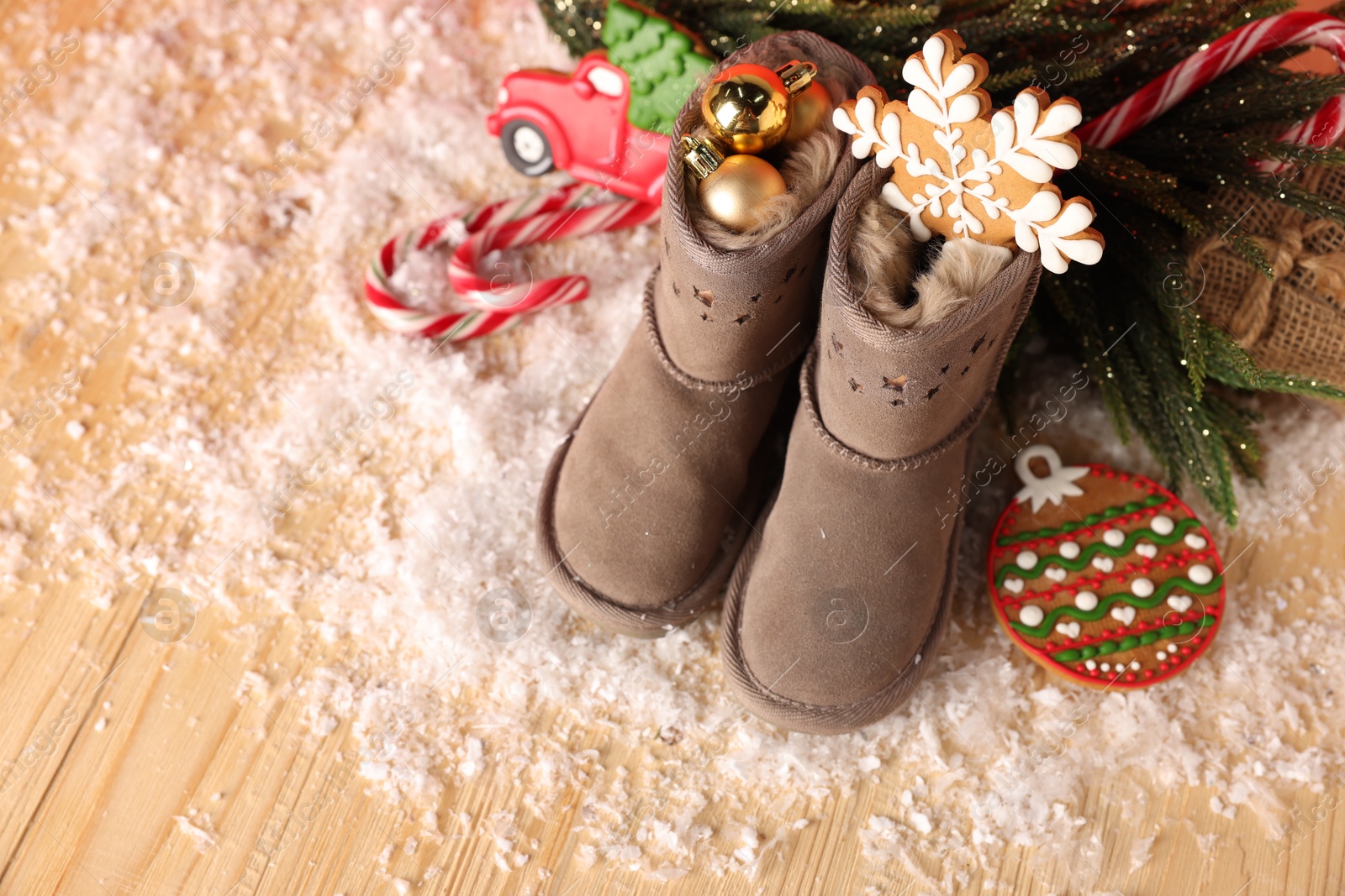 Photo of Saint Nicholas day. Boots with treats and festive decor on wooden table, above view. Space for text