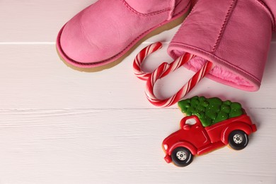 Photo of Saint Nicholas day. Boots with candy canes and cookie in shape of car on white wooden table, flat lay. Space for text