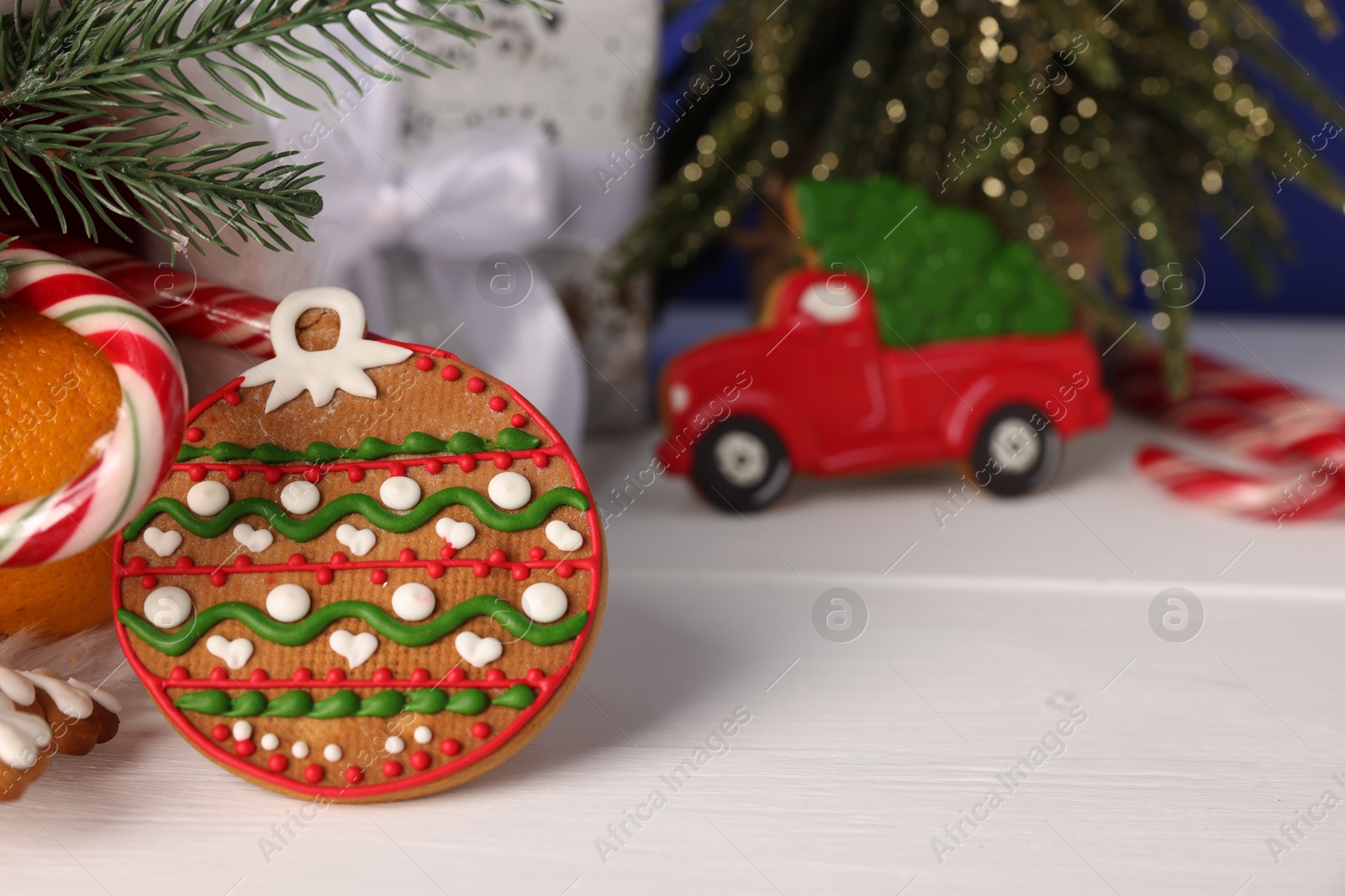Photo of Saint Nicholas day. Gingerbread cookies, candy cane, fir tree and gift box on white wooden table, closeup. Space for text