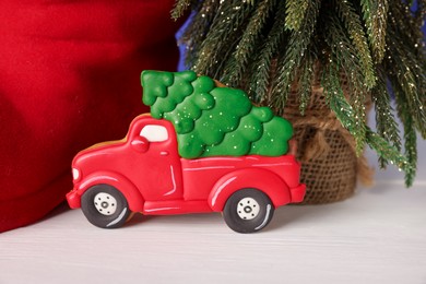 Photo of Saint Nicholas day. Tasty cookie in shape of car, fir tree and red boot on white wooden table, closeup