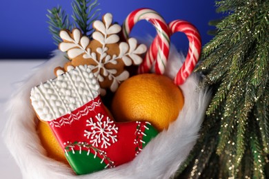 Photo of Saint Nicholas day. Boot with treats and fir tree on blurred background, closeup