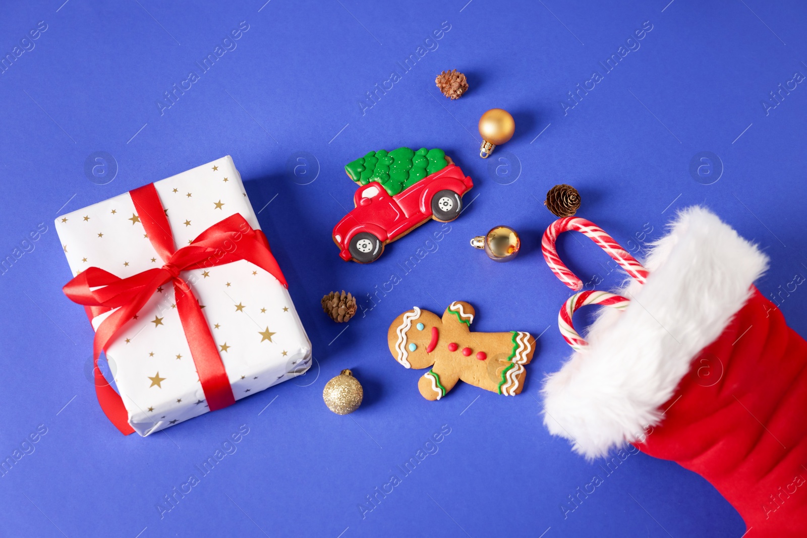 Saint Nicholas day. Red boot with treats, ornaments and gift box on blue background, flat lay Photo of Saint Nicholas day. Red boot with treats, ornaments and gift box on blue background, flat lay