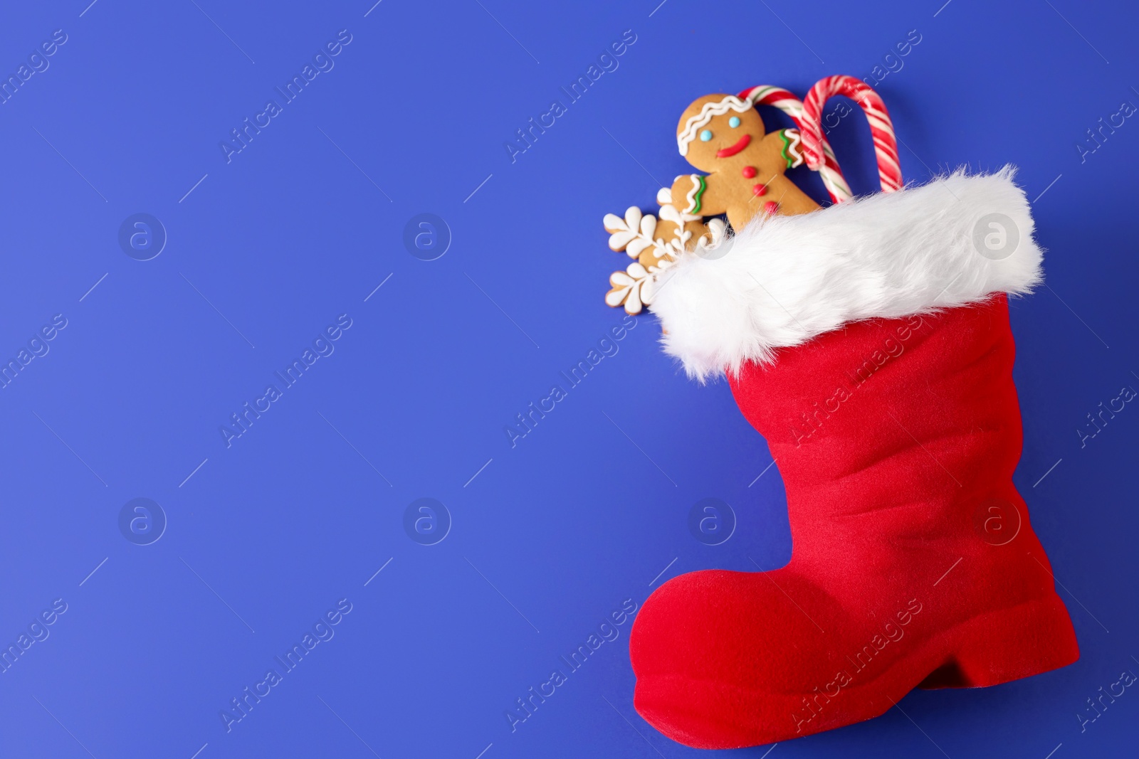 Saint Nicholas day. Red boot filled with treats on blue background, top view. Space for text Photo of Saint Nicholas day. Red boot filled with treats on blue background, top view. Space for text