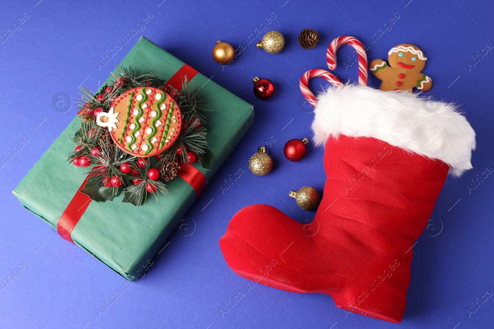 Saint Nicholas day. Red boot with treats, ornaments and gift box on blue background, flat lay Photo of Saint Nicholas day. Red boot with treats, ornaments and gift box on blue background, flat lay