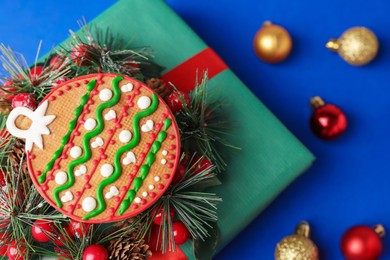 Photo of Saint Nicholas day. Gingerbread cookie, festive decor and gift box on blue background, flat lay