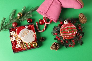 Photo of Saint Nicholas day. Boot with treats and festive decor on green background, flat lay